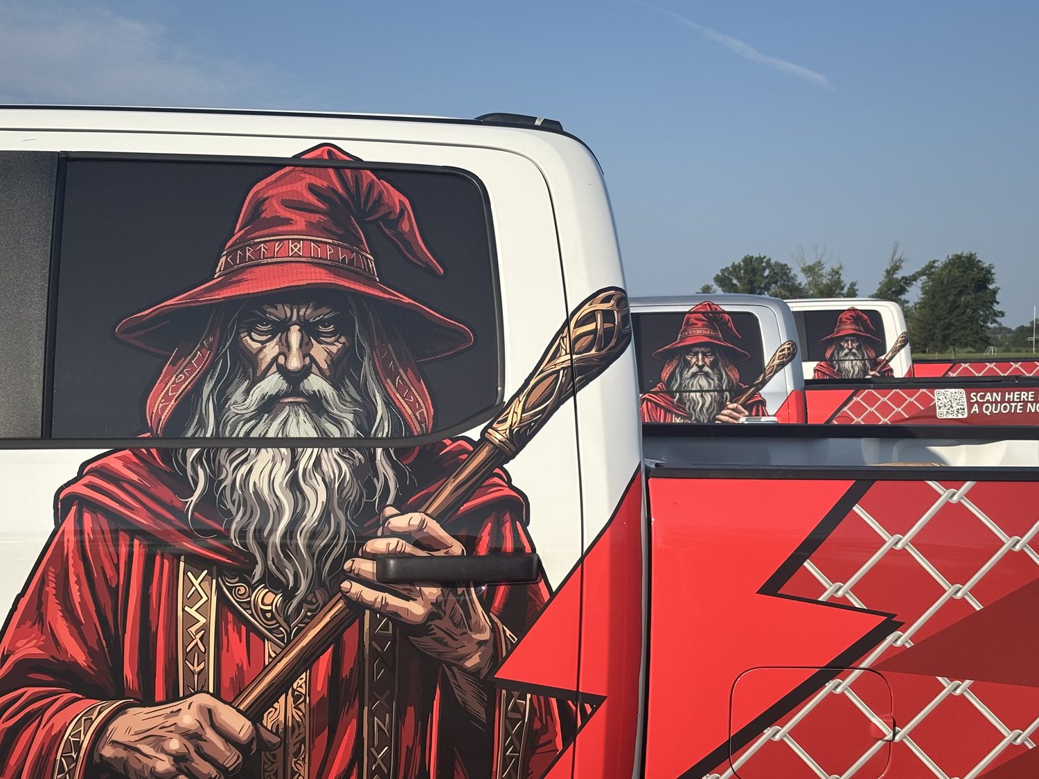 The wizard artwork on the side of a Fence Wizards truck, with two more wrapped trucks lined up behind it